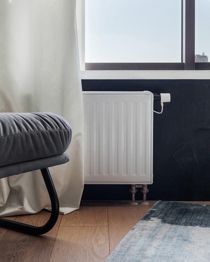 Flacher Heizkörper-Typ unter Fenster in modernem Wohnraum mit dunkler Wand