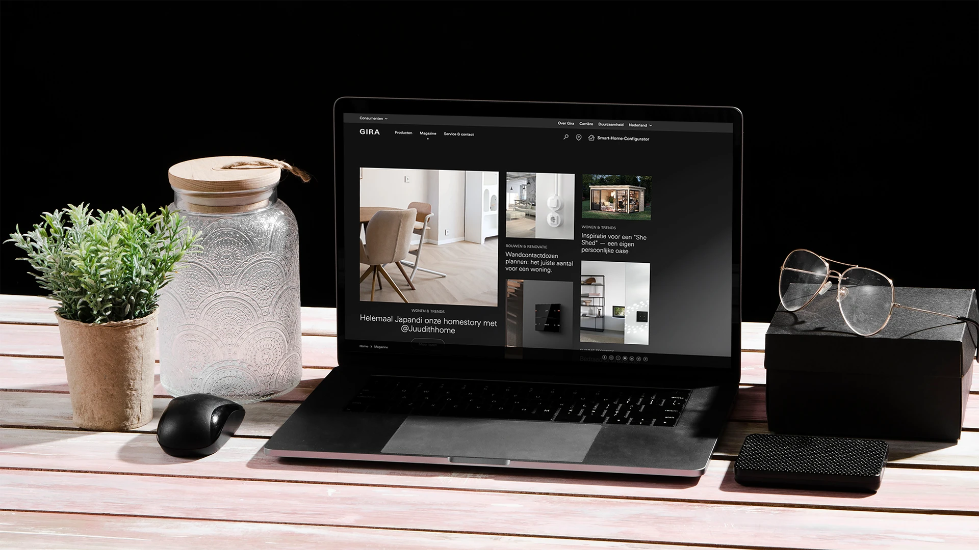 Moderne werkplek met de Gira website op een laptop en diverse accessoires.