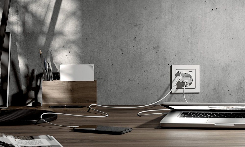 USB-Steckdose am Schreibtisch lädt Smartphone und Laptop direkt ohne separates Netzteil.