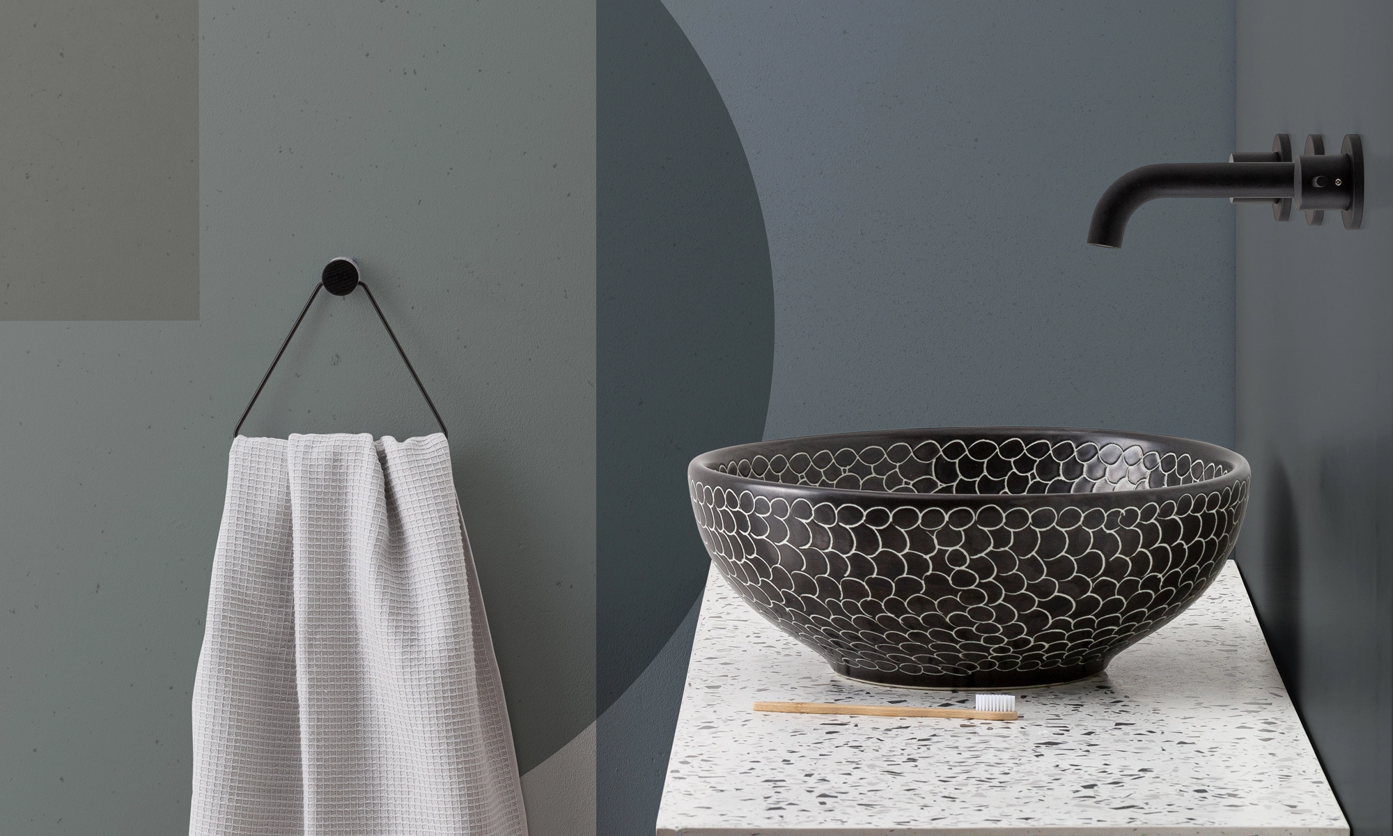 Ein modernes Waschbecken mit gemusterter Oberfläche neben einem aufgehängten Handtuch zeigt Tapetentrends mit geometrischen Formen im Hintergrund.