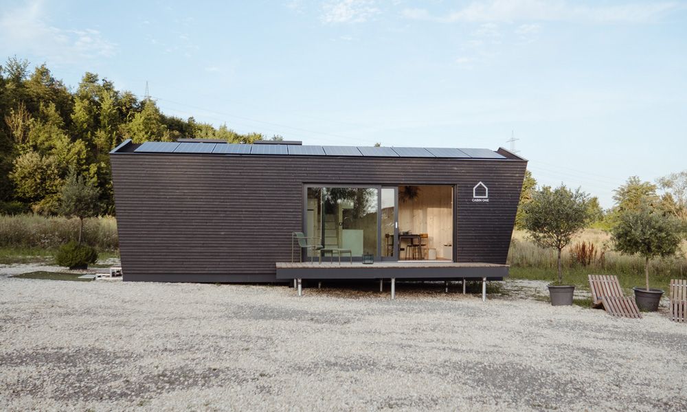 Modernes Tiny House „Cabin One“ mit dunkler Holzfassade und Solarpanels.