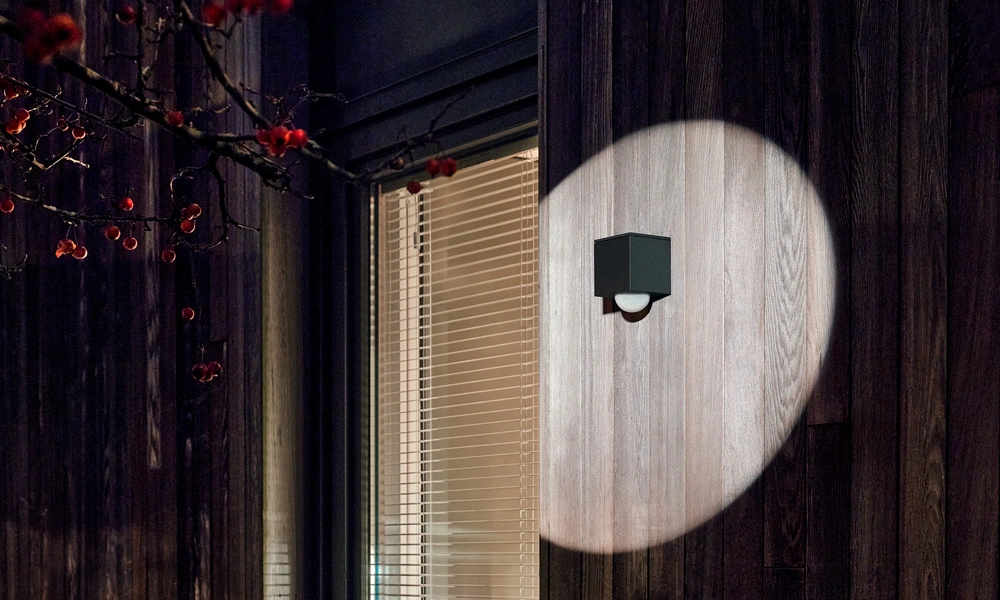 Gira Bewegungsmelder Cube, Schwarz, an Holzfassade, bei Dunkelheit