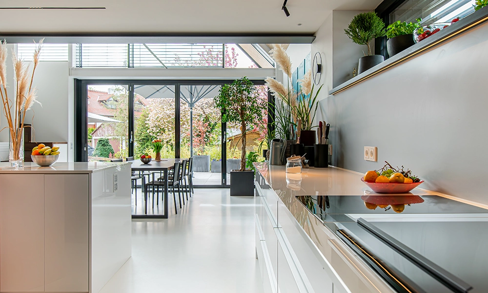 Eine modernisierte Küche mit eleganter Ausstattung und großem Essbereich, der durch Glaswände viel Tageslicht erhält.