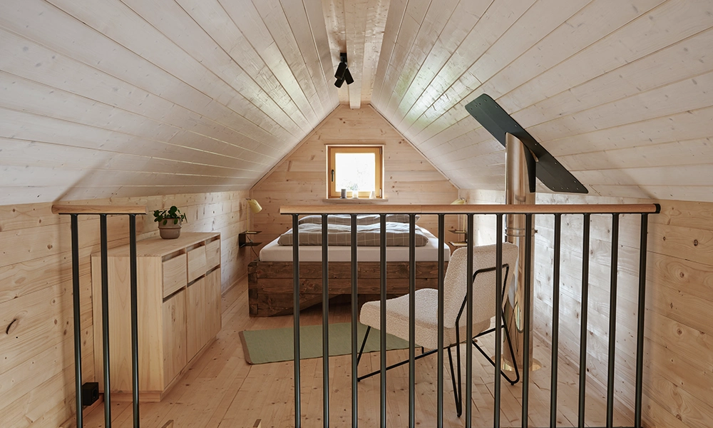 Ein Dachzimmer in einem Organic Tiny House mit modularem Design, Holzwänden und einer kleinen Sitzecke.