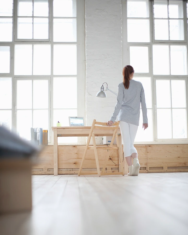 Helles Arbeitszimmer im skandinavischen Wohnstil mit großen Fenstern, Holzmöbeln und minimalistischer Einrichtung.