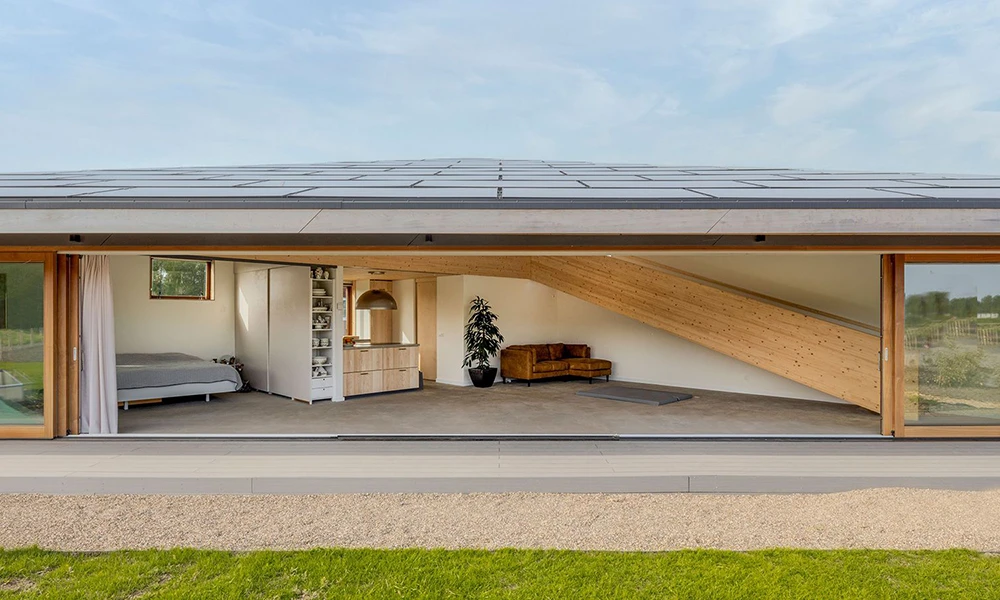 Bungalowartiges Haus in Frontalansicht mit leicht gespitztem Dach. Innen mit natürlichen Materialien ausgestattet.