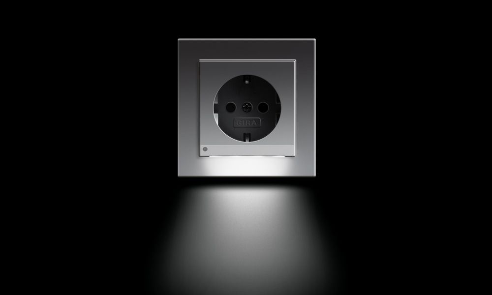 Gira SCHUKO-Steckdose mit LED-Orientierungsleuchte in Reinweiß glänzend bei Dunkelheit